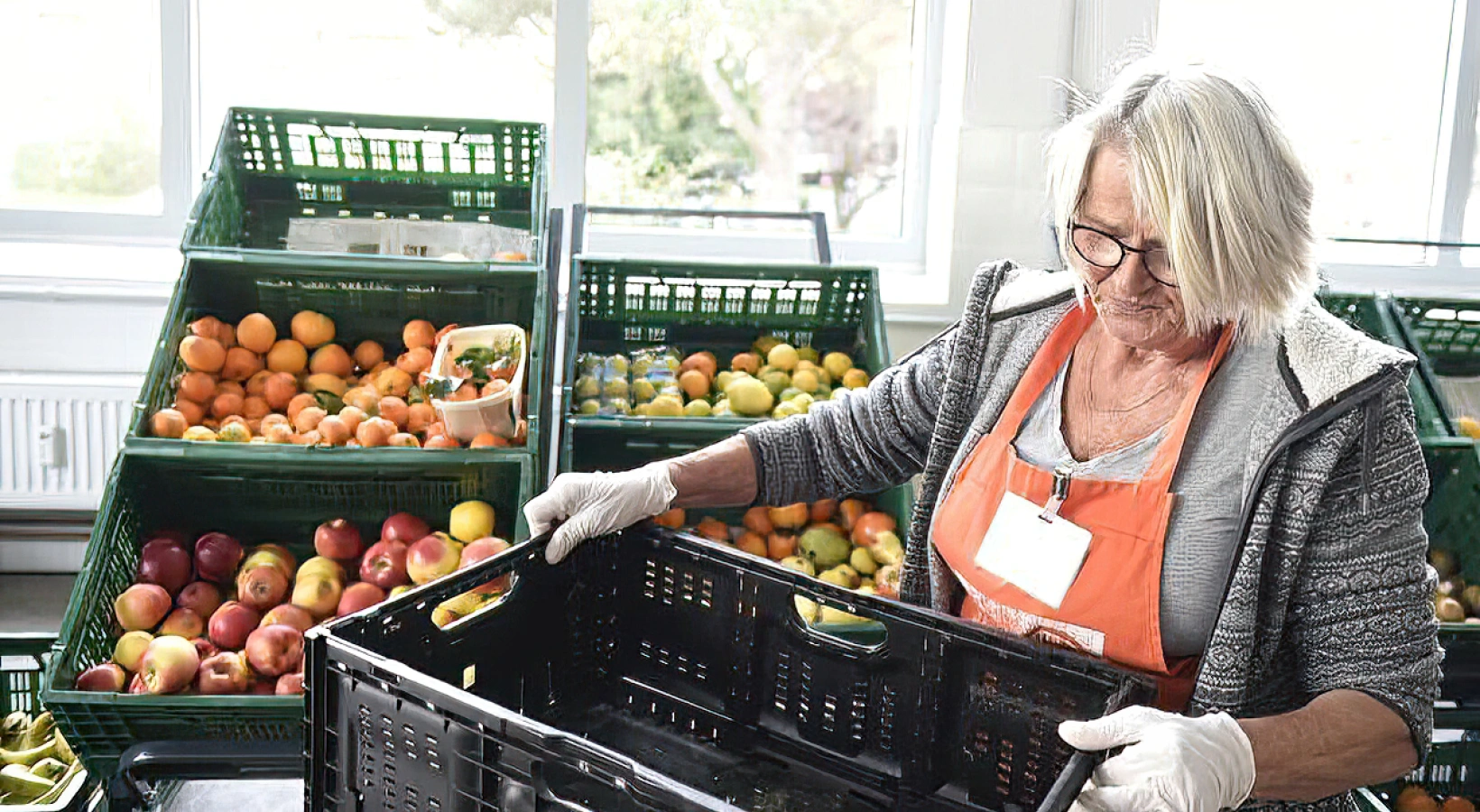 Frau in einem Obstladen die eine Kiste in der Hand hat und arbeitet