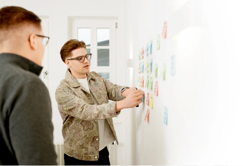 Man sieht, wie Post-its bei einen Workshop mit der Werbeagentur aus Bayreuth an die Wand geklebt werden