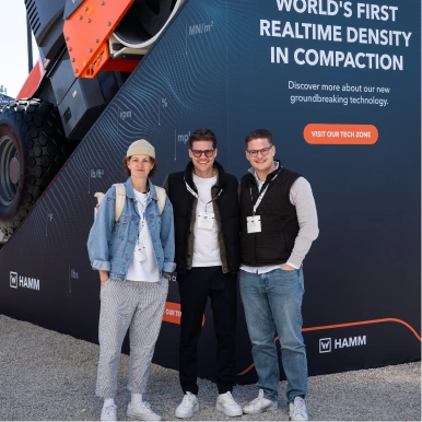 3 junge Erwachsene vor einer Walze auf der bauma