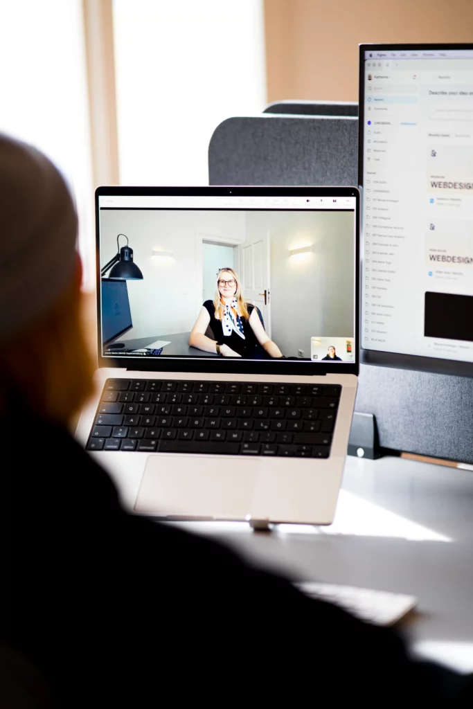 Person am Laptop in einer Videokonferenz mit einer Frau auf dem Bildschirm
