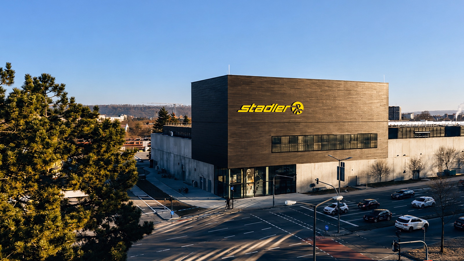 Moderner, kubischer Gebäudekomplex mit dunkelgrauer Fassade und gelbem "Stadler"-Logo an einer Straßenkreuzung in Regensburg